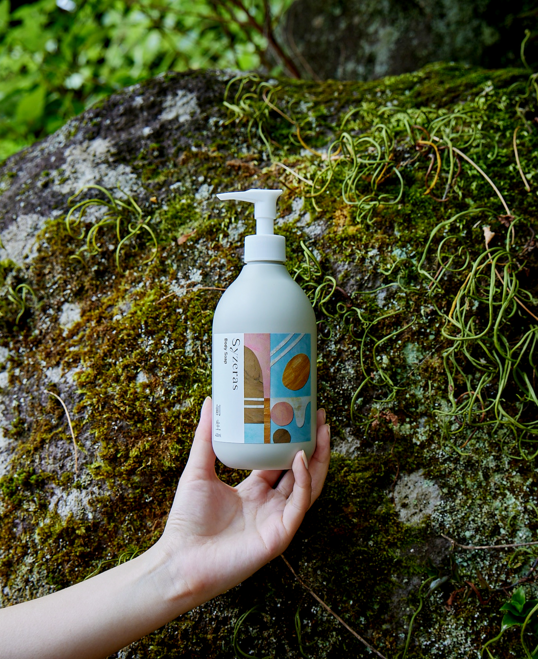 自然の中でシゼラスボディソープ創生を手に持っている女性